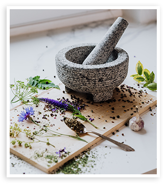 Stone mortar and pestle with fresh herbs and botanicals.