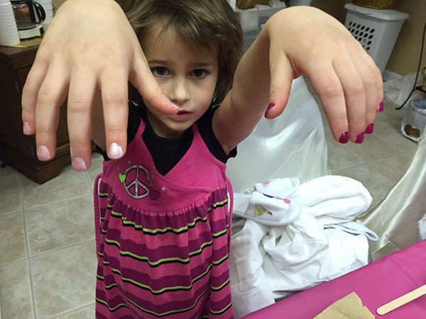 Child showing painted nails at a spa party